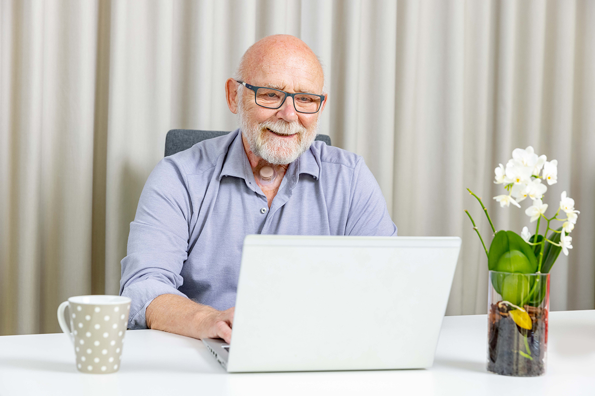 laryngectomy patient sitting at desk using laptop