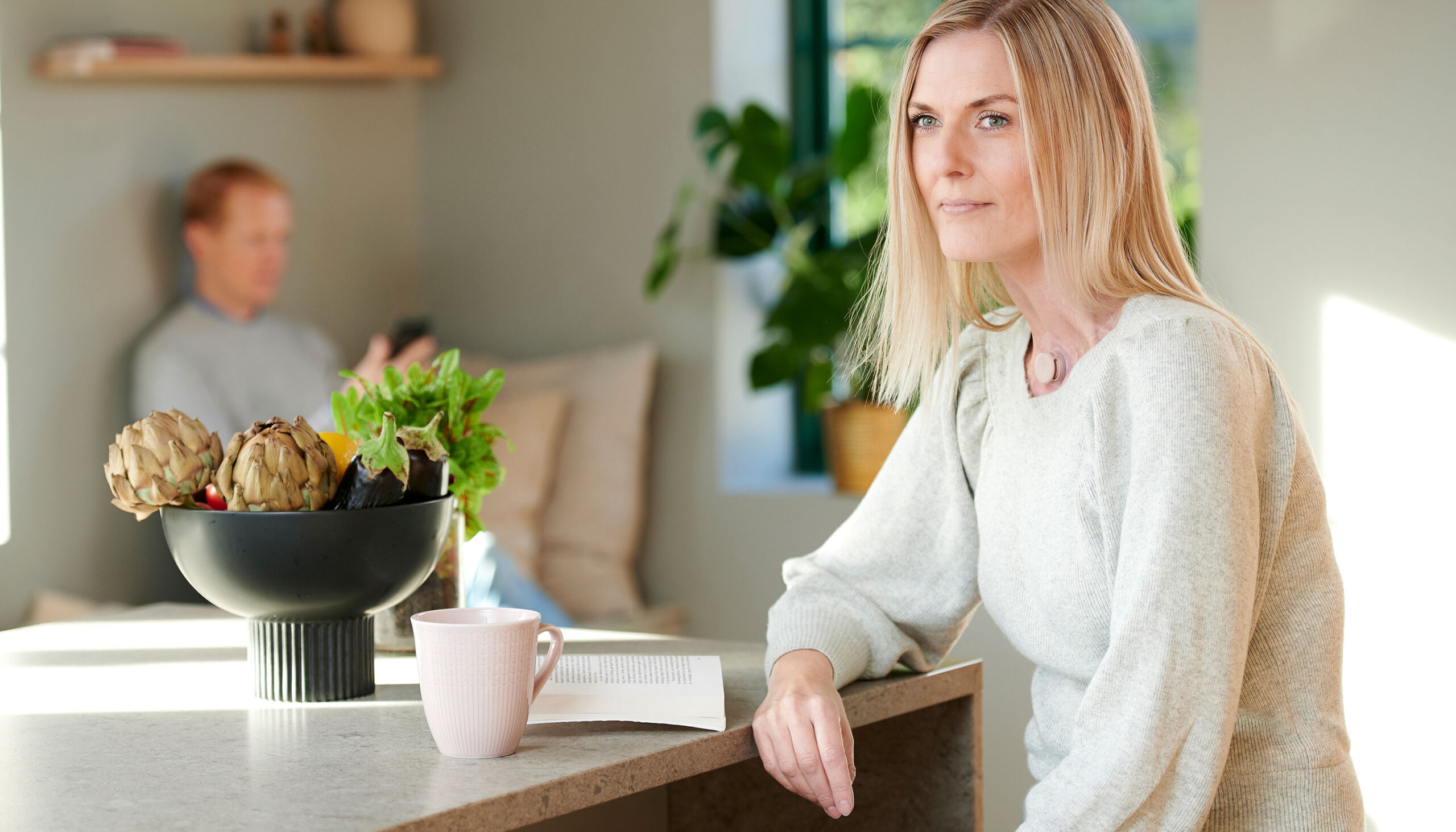 Young women with a neck stoma sitting at the dining table while using Provox life home HME.